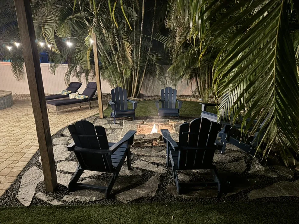 Landscaped patio with fire pit and string lights in the evening